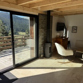 Salon du chalet au lac de Payolle, avec vue sur les montagnes et le lac.